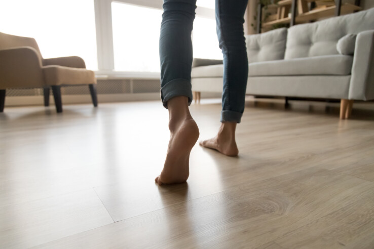 Une personne pieds nus sur un parquet dans un appartement – image symbolique illustrant les bruits d'impact et l'isolation acoustique dans un immeuble.