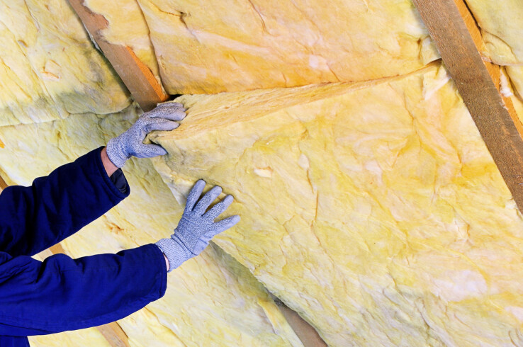 Un artisan pose des panneaux isolants entre les chevrons afin d'améliorer l'isolation thermique du toit.