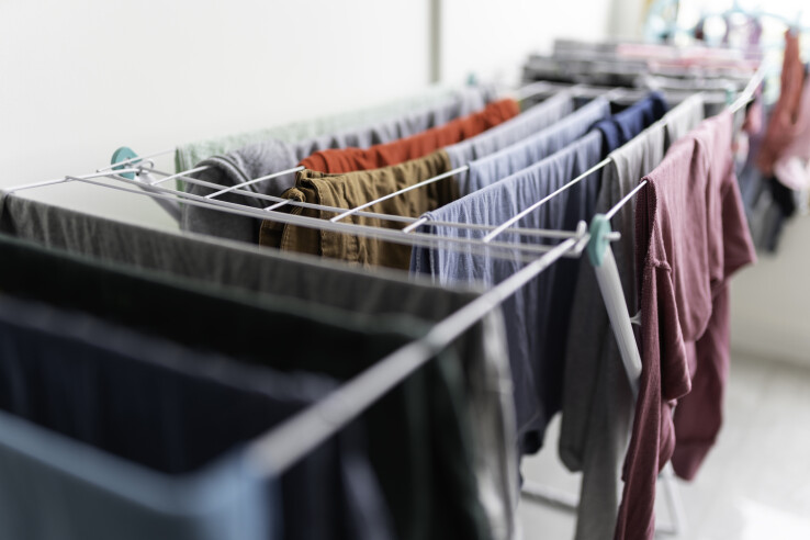 Une buanderie commune dans un immeuble collectif, où du linge est étendu sur plusieurs étendoirs.