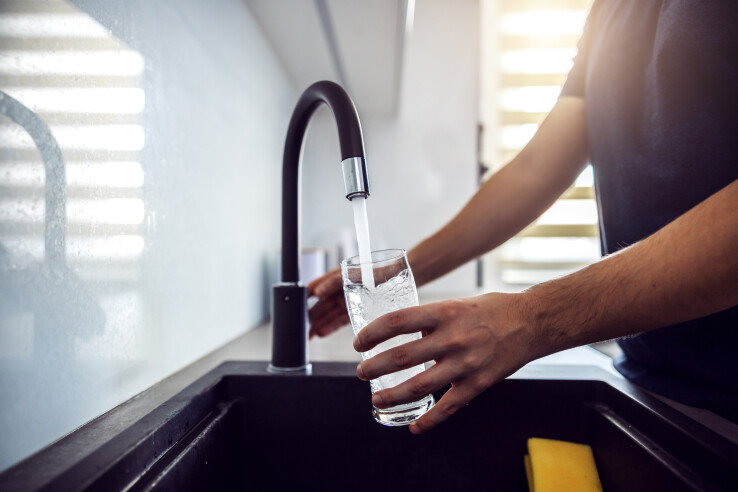 Une personne remplit un verre d'eau du robinet, en référence à un adoucisseur d'eau.