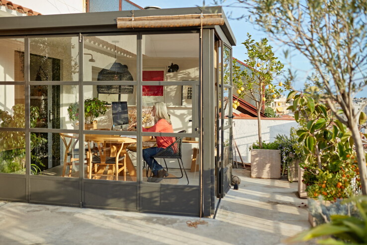 Une véranda à façade vitrée, offrant un espace de vie et de travail lumineux sur une terrasse
