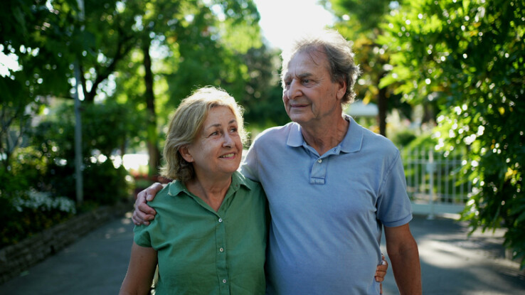 Un couple de personnes âgées se promène ensemble dans la nature et réfléchit à l'avenir de son logement pour ses vieux jours.
