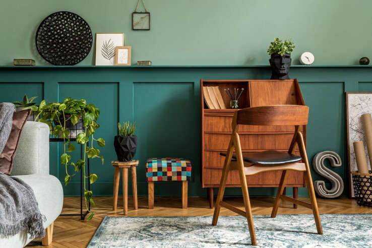 Salon de style vintage avec un mur vert, des meubles en bois, des plantes d'intérieur et des objets de décoration.